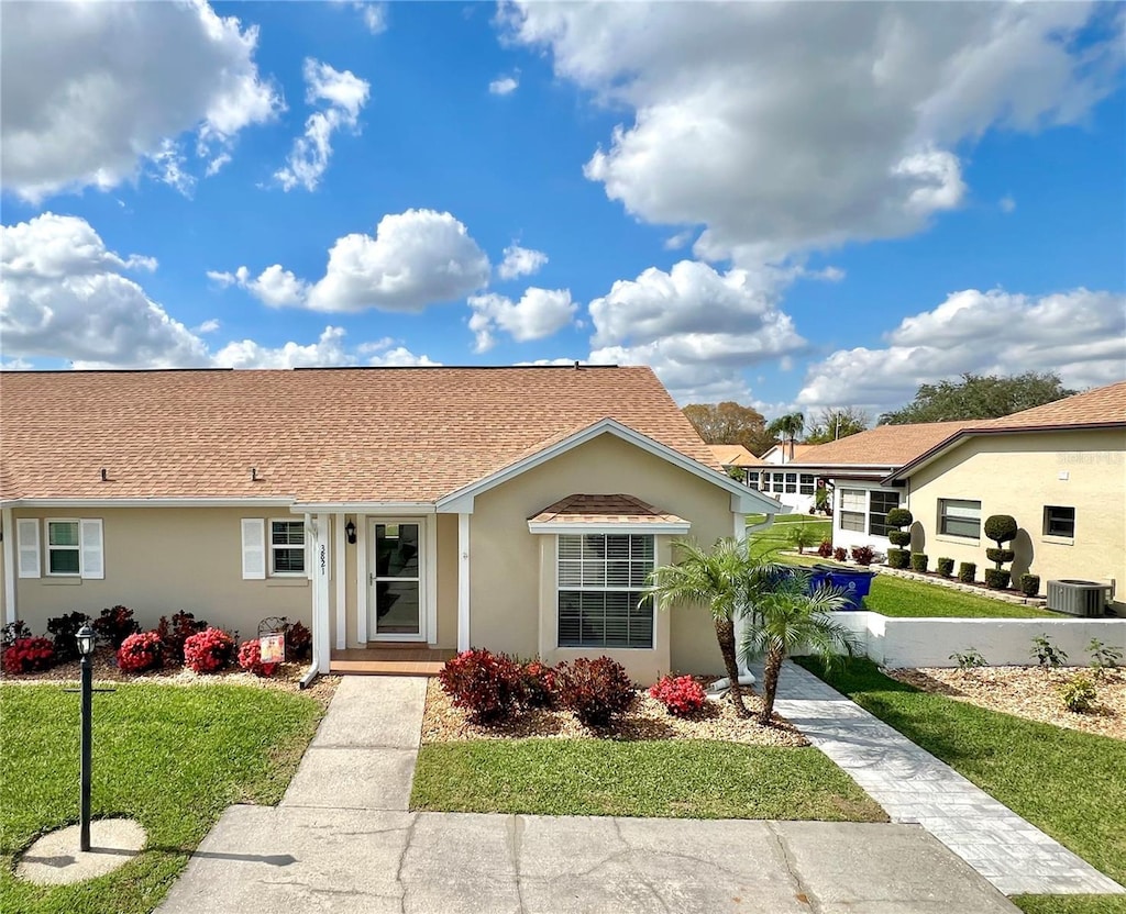 view of front of home with central AC and a front lawn