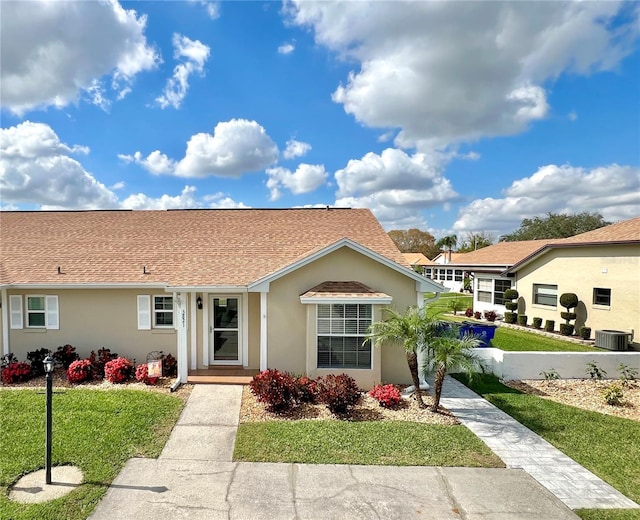 view of front of home with central AC and a front lawn