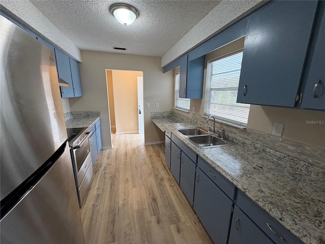 kitchen with blue cabinets, sink, a textured ceiling, appliances with stainless steel finishes, and light hardwood / wood-style floors