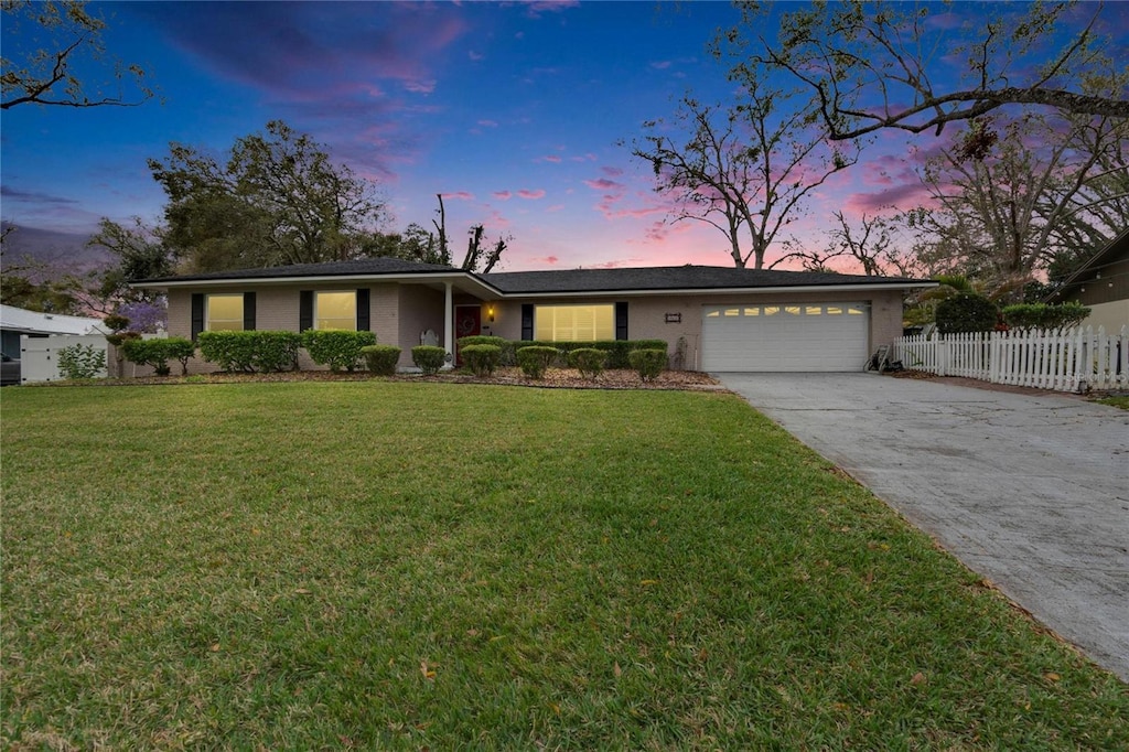 ranch-style house with a garage and a yard