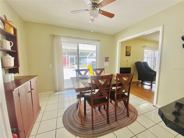 tiled dining area with ceiling fan and a textured ceiling