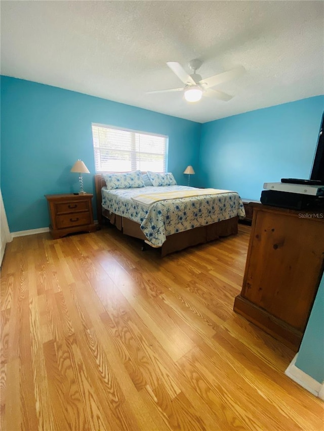 bedroom featuring a textured ceiling, ceiling fan, and light wood-type flooring