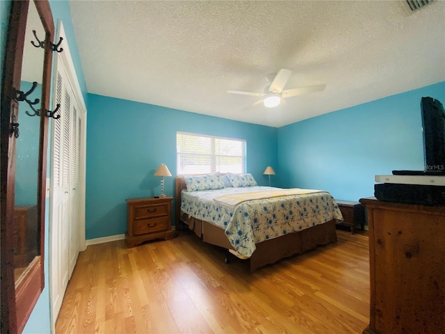 bedroom featuring ceiling fan, a textured ceiling, light wood-type flooring, and a closet