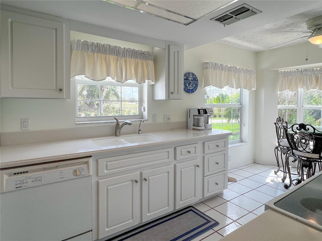 kitchen with light countertops, white cabinetry, dishwasher, and a sink