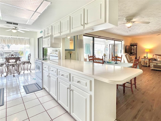 kitchen with ceiling fan, white appliances, visible vents, white cabinets, and light countertops