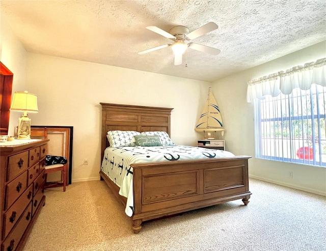 bedroom featuring light colored carpet, ceiling fan, a textured ceiling, and baseboards