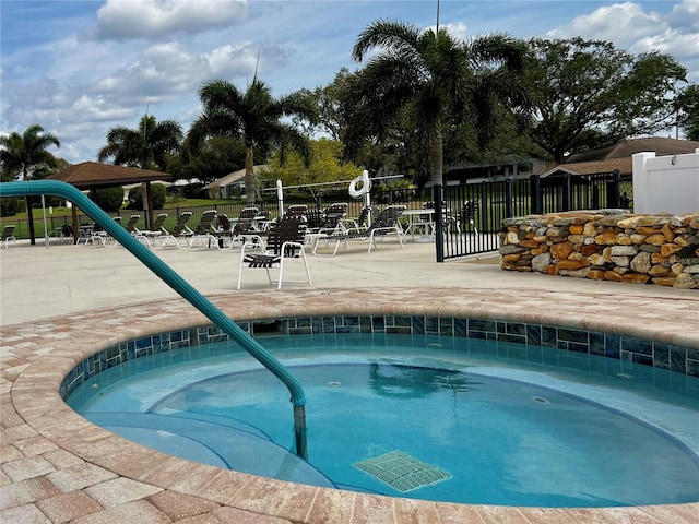 view of swimming pool featuring fence and a hot tub