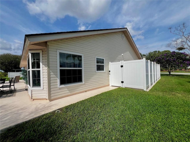 back of property with a lawn, a patio area, fence, and a gate
