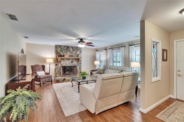 living room with wood-type flooring, visible vents, a fireplace, and a textured ceiling