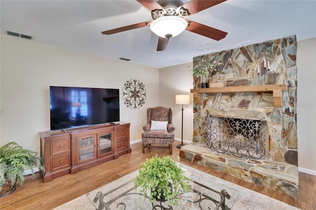 living area featuring a fireplace, visible vents, and wood finished floors