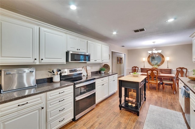 kitchen featuring stainless steel appliances, visible vents, white cabinetry, light wood-type flooring, and pendant lighting