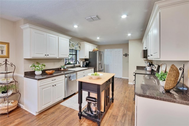 kitchen featuring light wood finished floors, visible vents, appliances with stainless steel finishes, white cabinets, and a sink