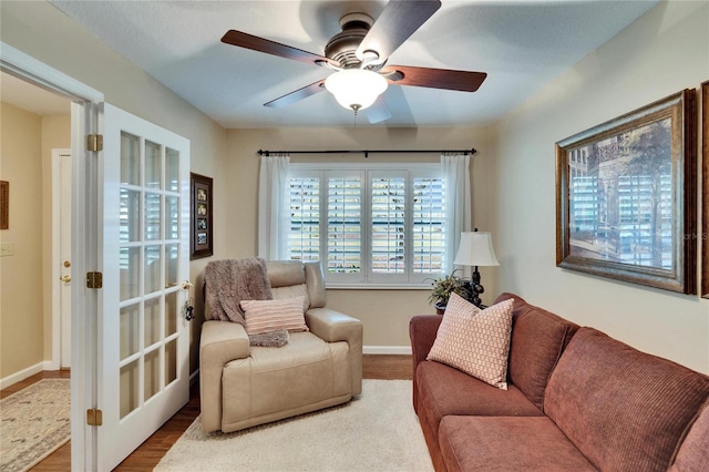 living area featuring ceiling fan, wood finished floors, and baseboards