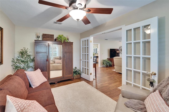 living room with a ceiling fan, french doors, visible vents, and light wood finished floors