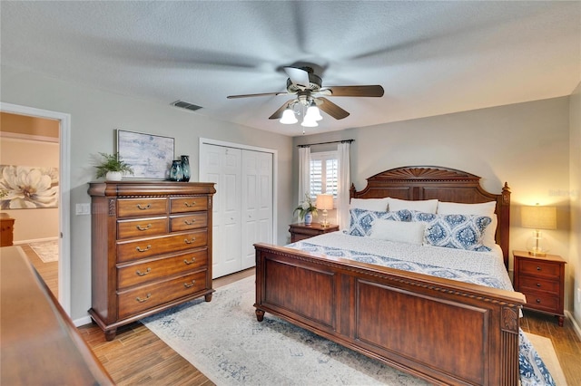 bedroom with light wood finished floors, a closet, visible vents, and a ceiling fan