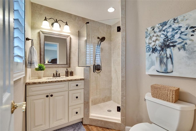 full bathroom with a stall shower, vanity, and toilet