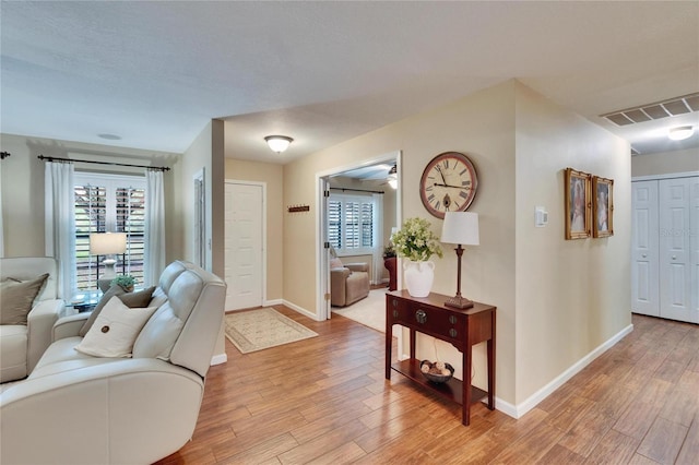 foyer entrance with a wealth of natural light, light wood-type flooring, visible vents, and baseboards