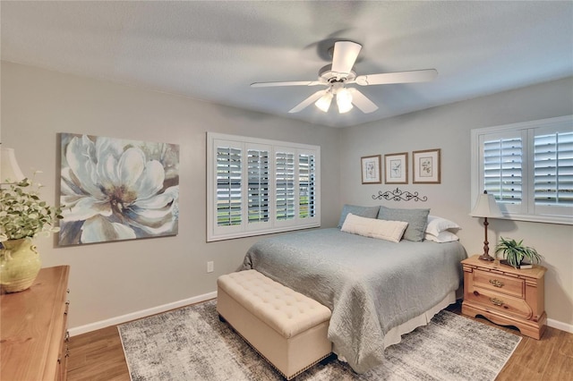 bedroom with ceiling fan, baseboards, and wood finished floors