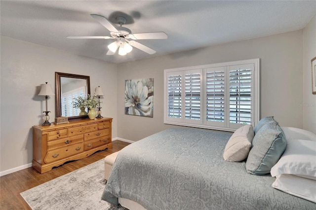 bedroom with ceiling fan, wood finished floors, and baseboards