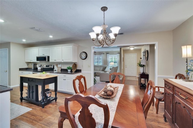 dining area with light wood-type flooring, an inviting chandelier, visible vents, and recessed lighting