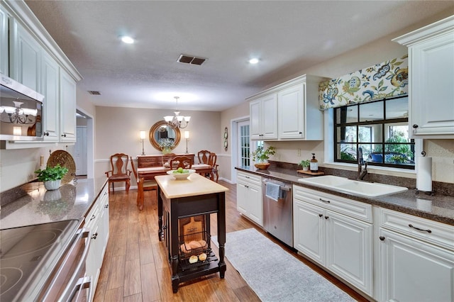 kitchen with a notable chandelier, appliances with stainless steel finishes, a sink, and white cabinets