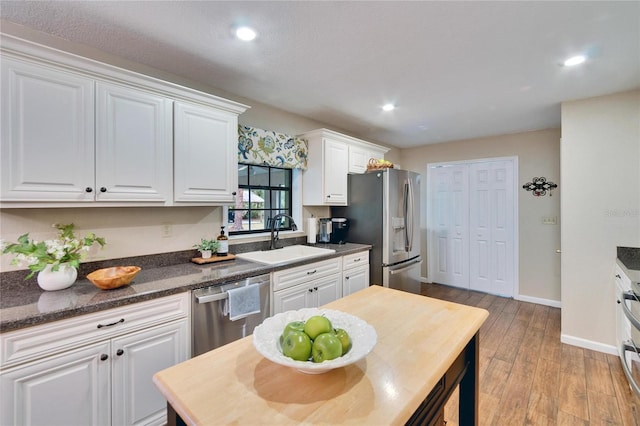 kitchen featuring light wood finished floors, recessed lighting, appliances with stainless steel finishes, white cabinetry, and a sink