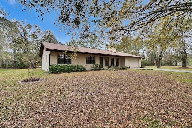 ranch-style house with an attached garage, stucco siding, and a front yard