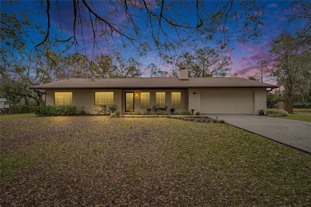 single story home featuring a yard, a chimney, stucco siding, concrete driveway, and an attached garage