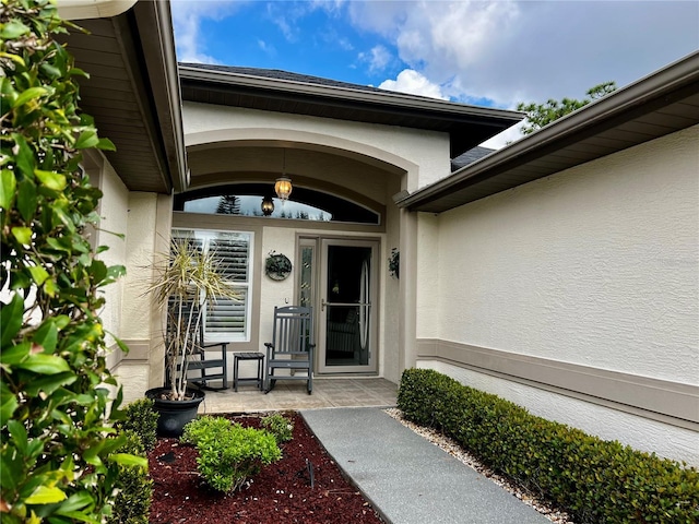 property entrance featuring a porch and stucco siding