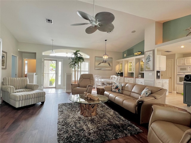 living room with high vaulted ceiling, light wood-style flooring, visible vents, baseboards, and a ceiling fan