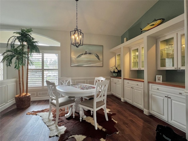 dining area with dark wood-style floors, a chandelier, a decorative wall, and a wainscoted wall