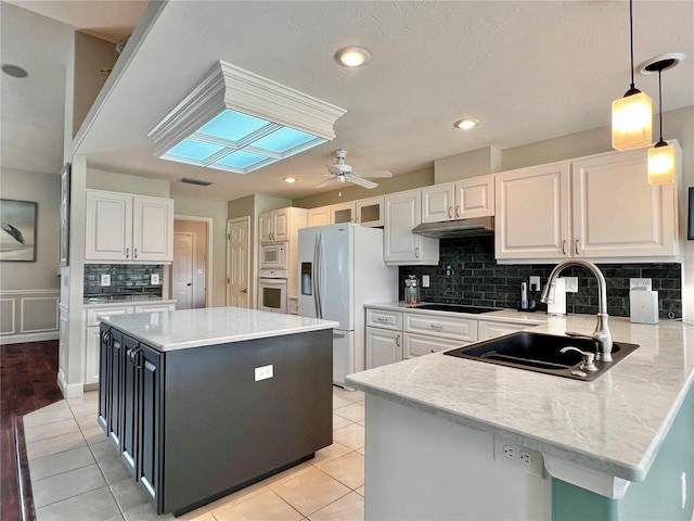 kitchen with a skylight, fridge with ice dispenser, a sink, built in microwave, and oven