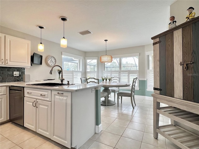 kitchen with light tile patterned floors, dishwashing machine, a sink, visible vents, and backsplash