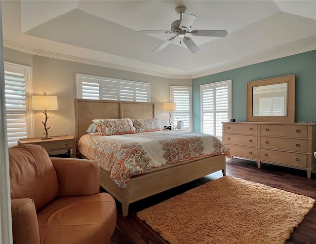 bedroom with ornamental molding, a raised ceiling, and dark wood finished floors