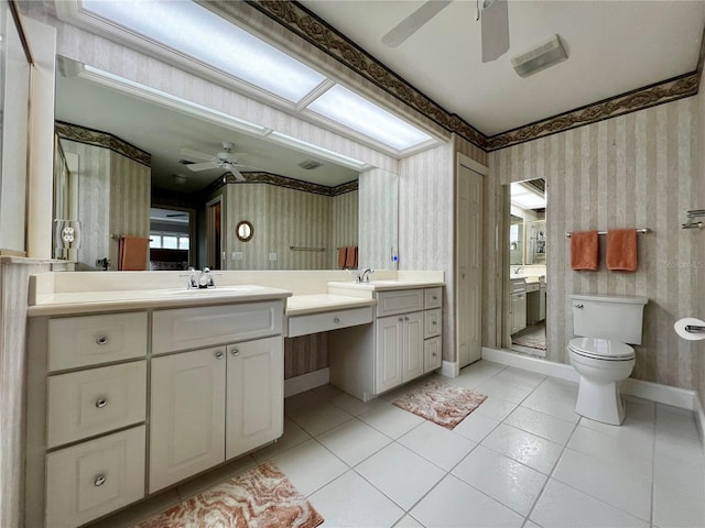 bathroom with toilet, wallpapered walls, baseboards, and vanity