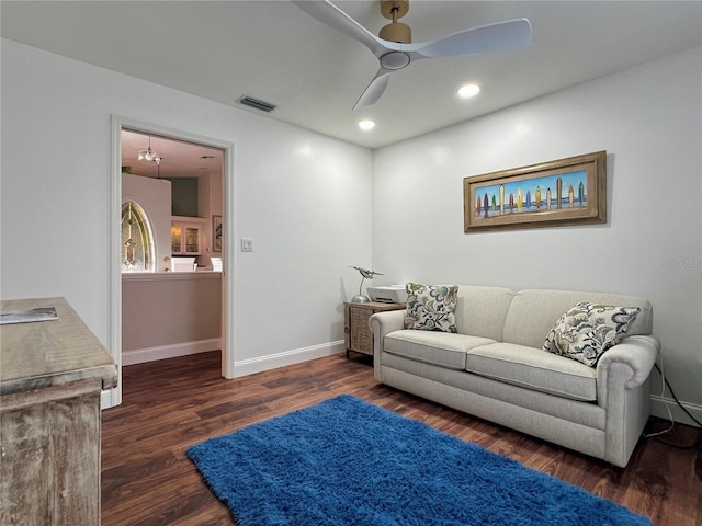 living room with a ceiling fan, visible vents, baseboards, and wood finished floors