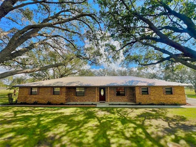 ranch-style home featuring brick siding, metal roof, and a front lawn