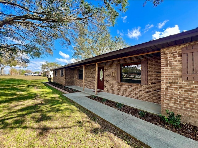 entrance to property featuring brick siding and a yard