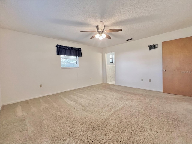 spare room with ceiling fan, a textured ceiling, carpet flooring, visible vents, and baseboards