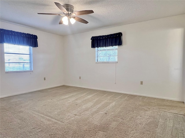 empty room with carpet, a textured ceiling, ceiling fan, and a wealth of natural light