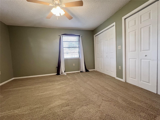 unfurnished bedroom with a ceiling fan, carpet flooring, a textured ceiling, and baseboards