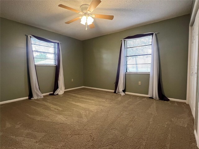 empty room featuring carpet floors, a healthy amount of sunlight, and ceiling fan