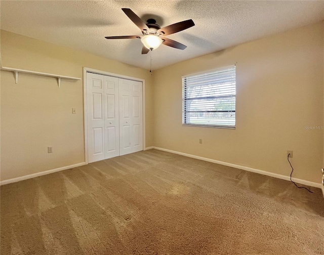 unfurnished bedroom with a textured ceiling, carpet floors, a closet, and baseboards