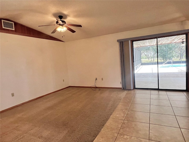 empty room featuring light tile patterned floors, light carpet, visible vents, baseboards, and vaulted ceiling