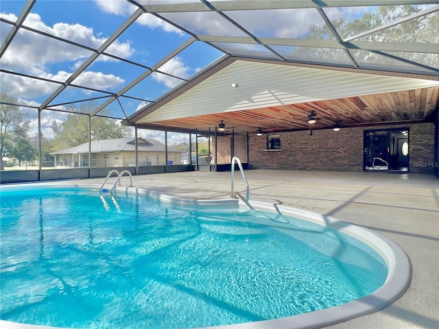 pool with a patio area, glass enclosure, and a ceiling fan