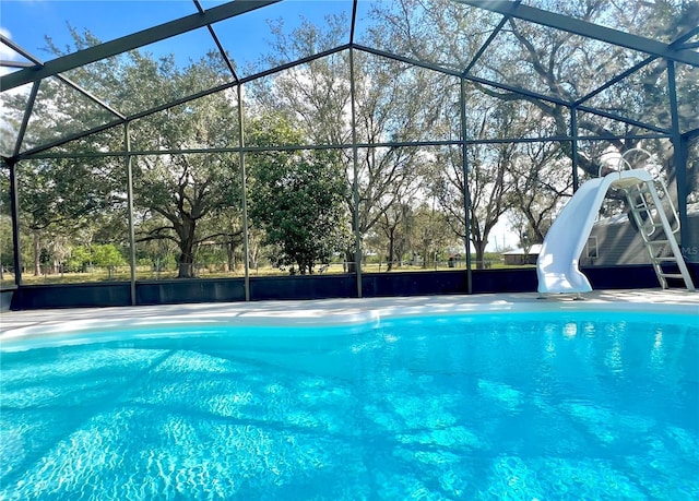 view of pool with a water slide and glass enclosure