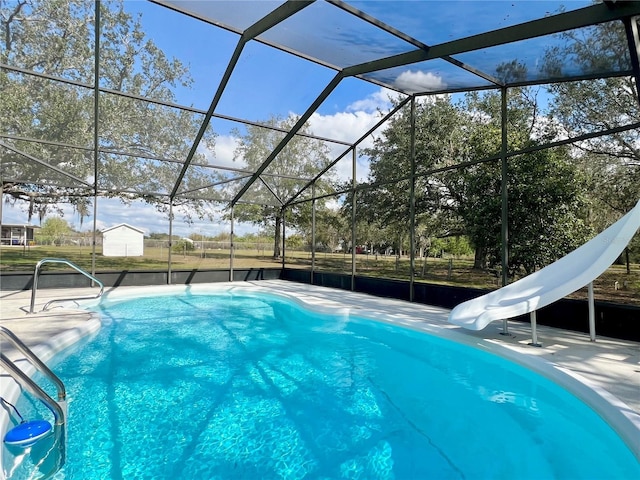 outdoor pool featuring glass enclosure, a water slide, a patio area, and an outdoor structure