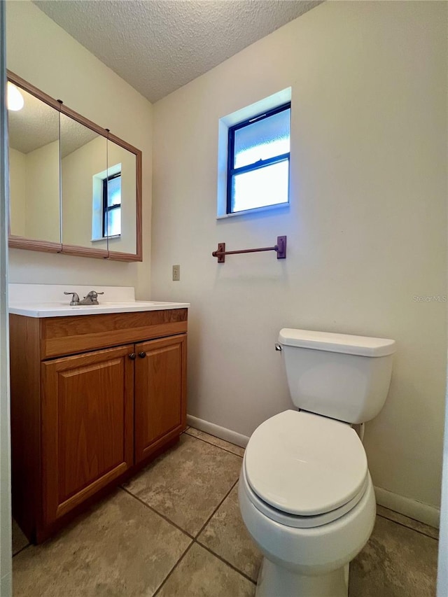 bathroom featuring baseboards, a textured ceiling, toilet, and vanity