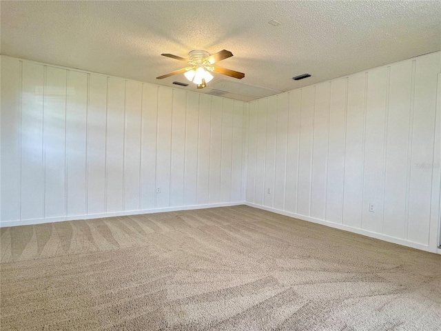 carpeted spare room with a ceiling fan, visible vents, and a textured ceiling