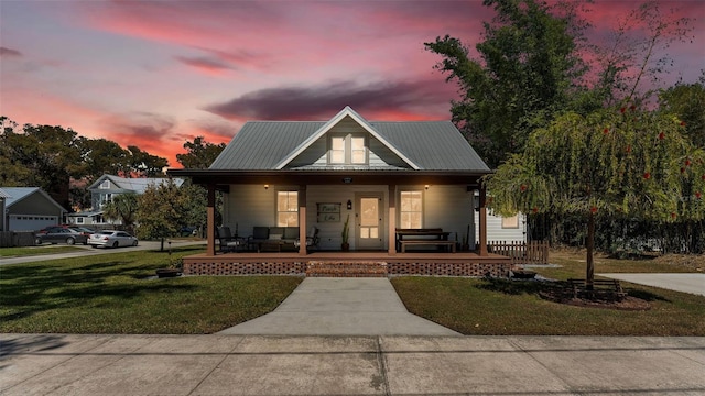 view of front of house with a front yard, covered porch, and metal roof